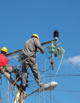 Low angle shot of electric linemen working on pole A low angle shot of electric linemen working on pole