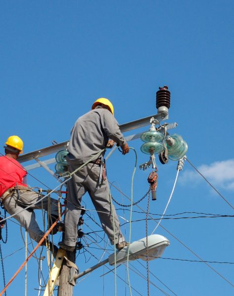 Low angle shot of electric linemen working on pole A low angle shot of electric linemen working on pole