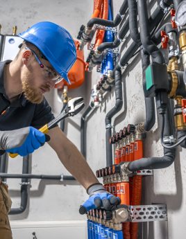 The technician checking the heating system in the boiler room. The technician checking the heating system in the boiler room. Adjusting heating valves in a residential building. A plumbing and heating technician works.